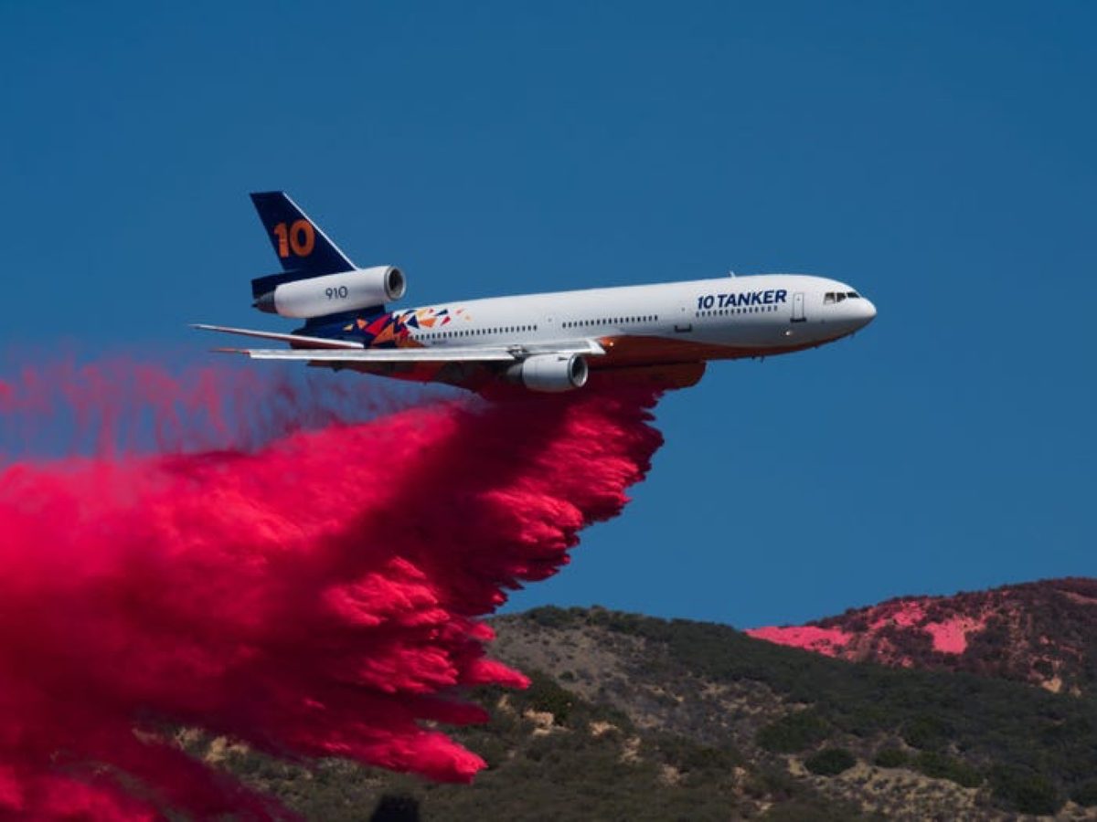 10 Tanker DC-10 air tanker dropping red fire retardant over a hillside