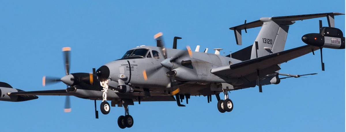 U.S. Army twin-turboprop surveillance aircraft in flight against a blue sky